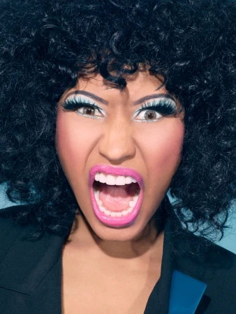 Close-up portrait of Nicki Minaj with voluminous black afro hair, dramatic false eyelashes, and open-mouth expression