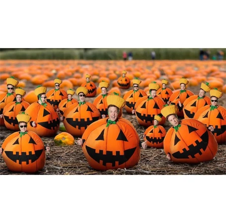 Group of people dressed in smiling pumpkin costumes, gathered in a pumpkin patch for a festive Halloween-themed event.