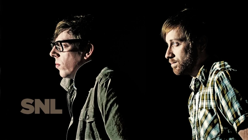 Profile portrait of two men against a black background with dramatic low-key lighting and visible SNL logo