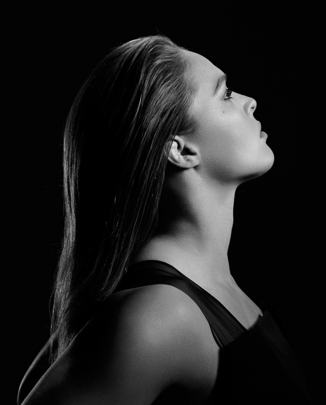 Black and white profile portrait of Ronda Rousey looking upward against a dark background by Mary Ellen Matthews.