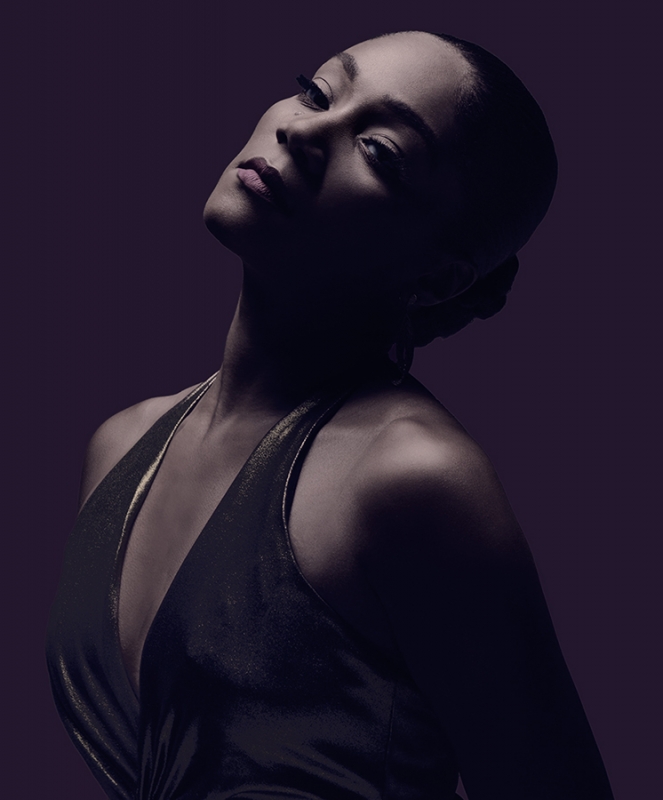 Portrait of a woman in a dark halter dress photographed by Mary Ellen Matthews with dramatic low-key lighting.