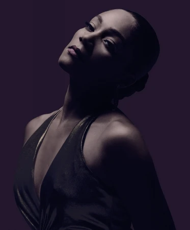 Portrait of a woman in a dark halter dress photographed by Mary Ellen Matthews with dramatic low-key lighting.