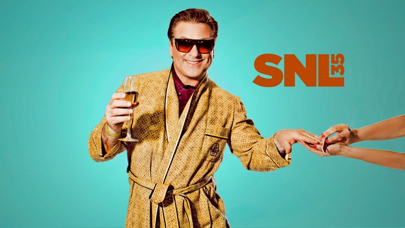 Man in patterned robe holding champagne glass in front of aqua background with SNL logo, receiving manicure from disembodied hands.