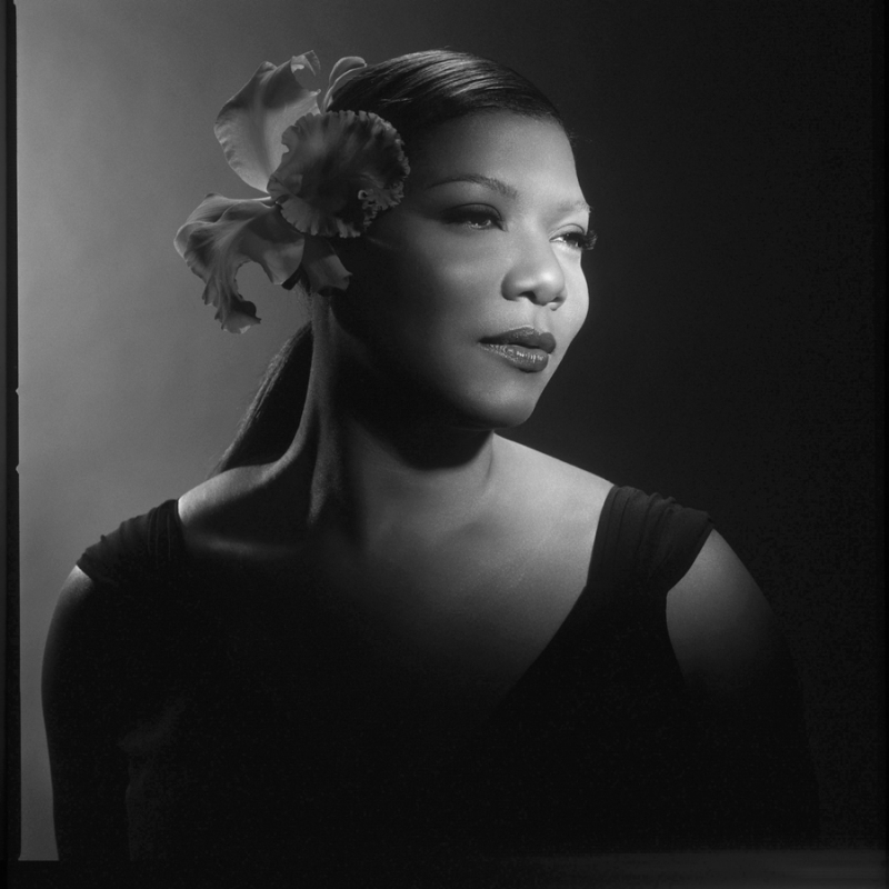 Monochrome portrait of Queen Latifah wearing a large flower in her hair and a dark sleeveless top