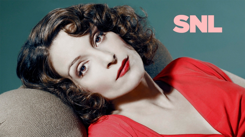 Portrait of a brunette woman with red lipstick and a red top resting on a couch, with 'SNL' text in the background.
