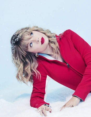 Taylor Swift wearing a red jacket and red lipstick posing against a snowy white background by Mary Ellen Matthews