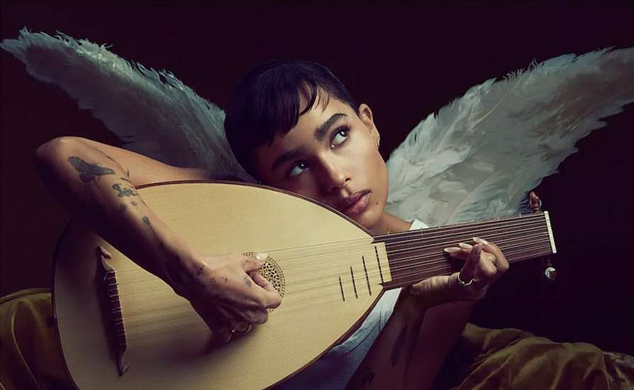 Woman poses with lute and angel wings against dark backdrop, looking up with dreamy expression, artistic, close-up.