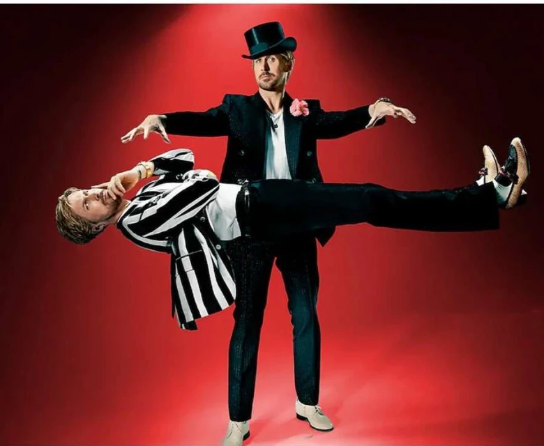 Two men pose in a studio shot: one in a black top hat and suit appears to be magically levitating the other in a striped jacket.