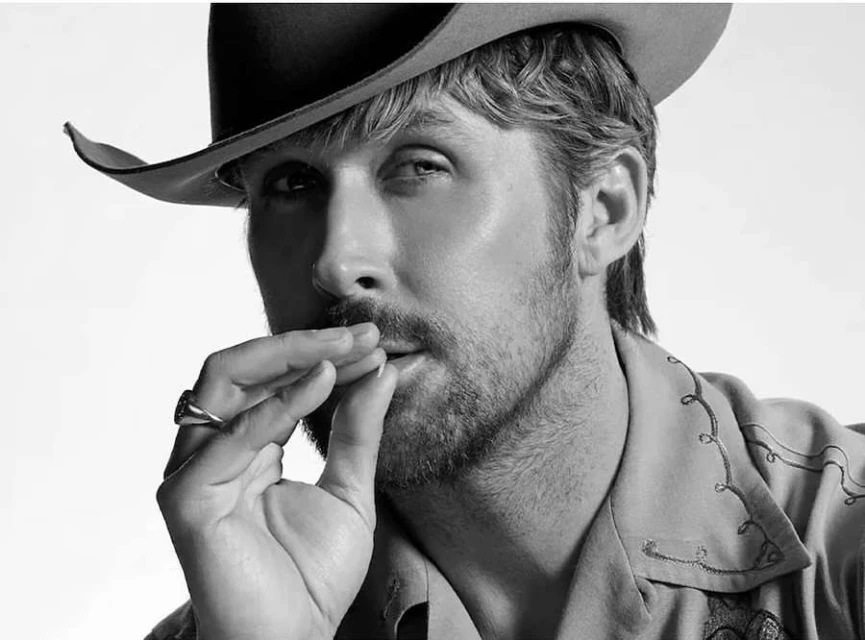 Black and white portrait of a man wearing a cowboy hat and button-down shirt with hand near his mouth, staring intently at the camera.