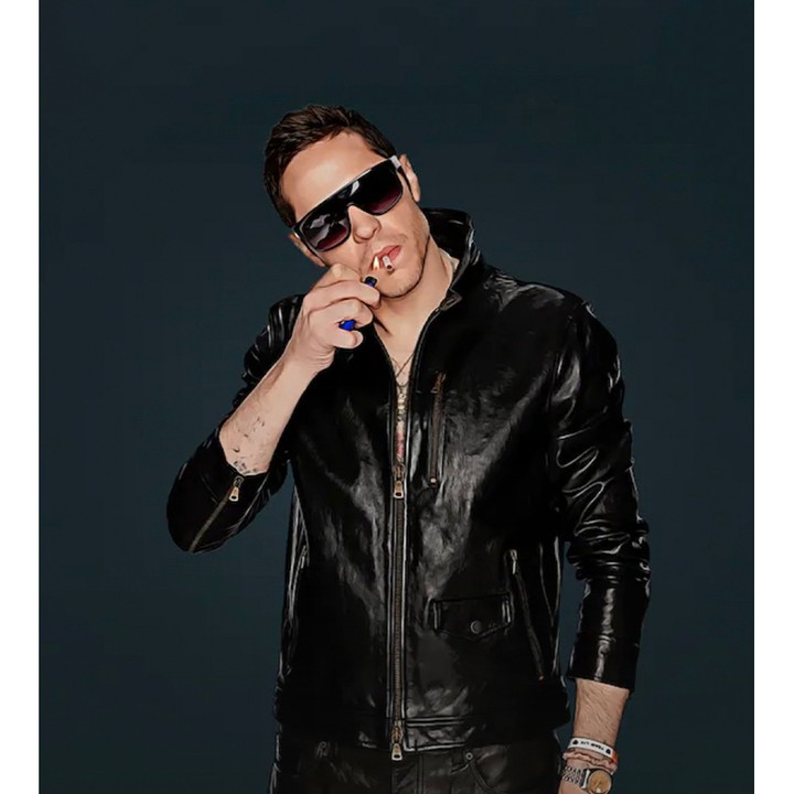 Man wearing sunglasses and a black leather jacket lighting a cigarette against a dark background