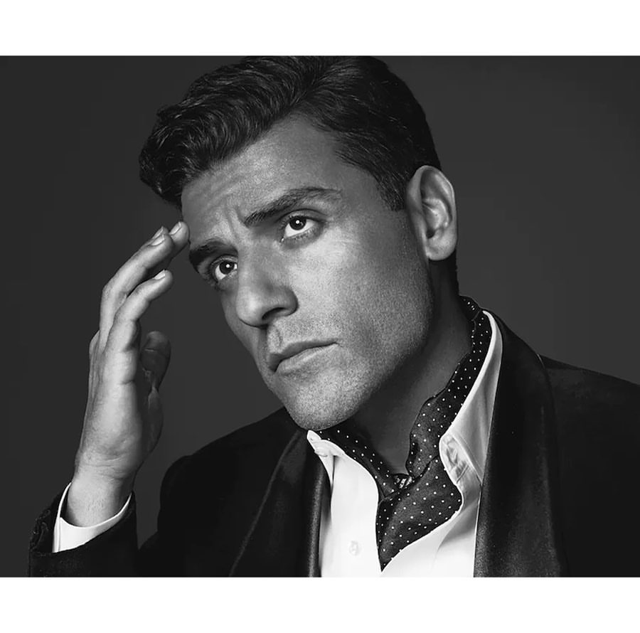 Black and white portrait of a man with dark hair, wearing a suit and ascot, holding his hand up to his forehead in a pensive pose.