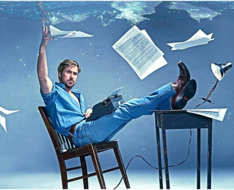 Adult male poses while seated at desk with a typewriter; papers fly through air in a surreal, underwater scene with blue hues.