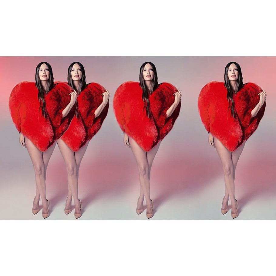 Three identical women pose in a studio wearing large, red, heart-shaped fluffy coats, nude-colored heels, and long brown hair.