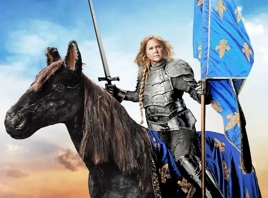 Woman in armor astride a horse holding a sword and a blue and gold flag, against a cloudy sky backdrop. Medieval theme.