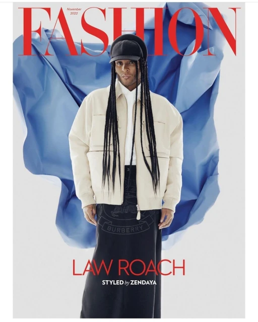 Magazine cover featuring Law Roach in a light-colored jacket and dark skirt, styled by Zendaya, against a blue fabric backdrop.