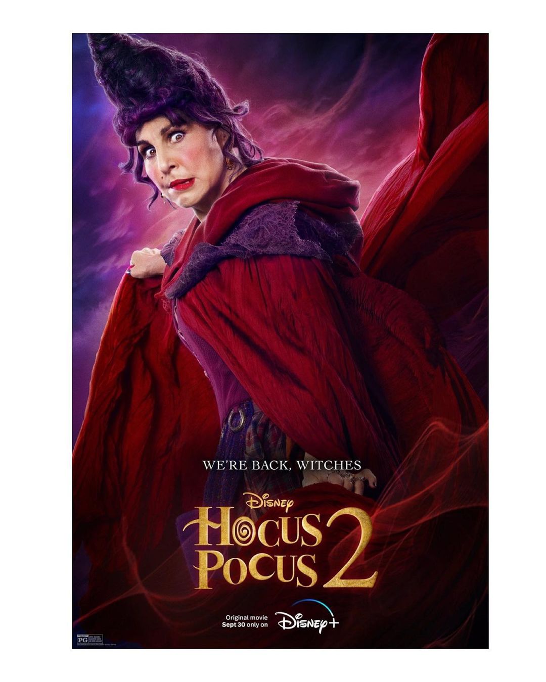 Promotional poster for Hocus Pocus 2 features an adult female with dark hair and dramatic make-up, wearing a red and purple witch costume.