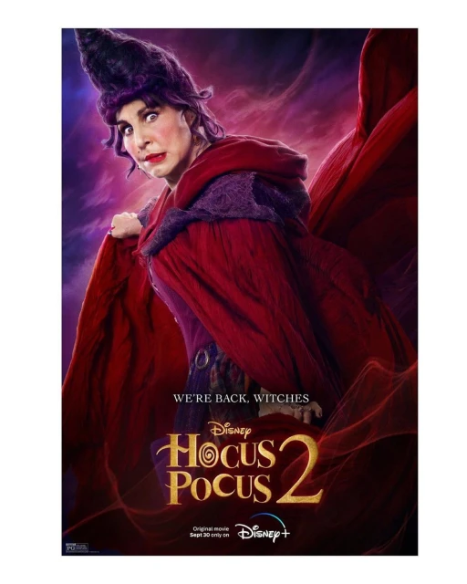 Promotional poster for Hocus Pocus 2 features an adult female with dark hair and dramatic make-up, wearing a red and purple witch costume.