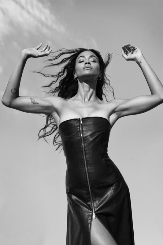 Black and white portrait of woman in strapless dress. The image features a sky background, adding depth and emphasizing the subject's pose.