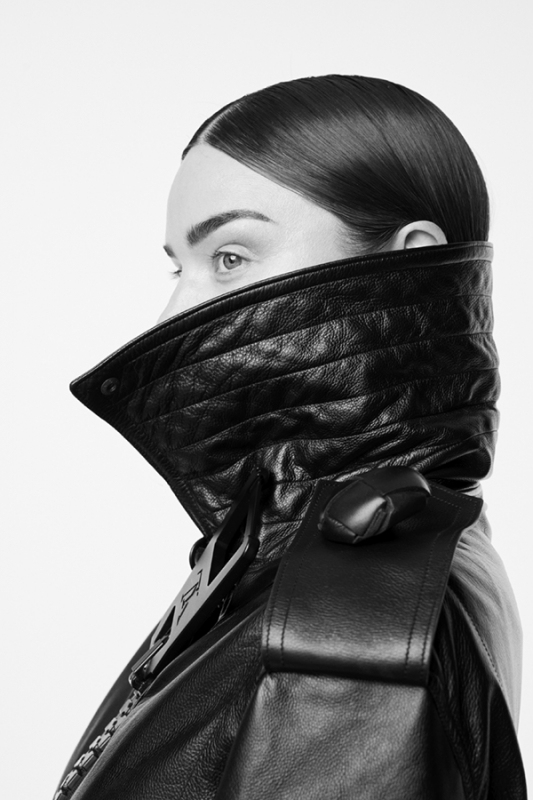 Profile shot of a woman wearing a black quilted leather jacket against a bright background, showcasing fashion and style.