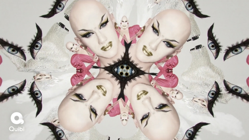 Surreal kaleidoscope image with the faces of a bald adult woman wearing makeup, geometric shapes, and floating eyes on a grey background.
