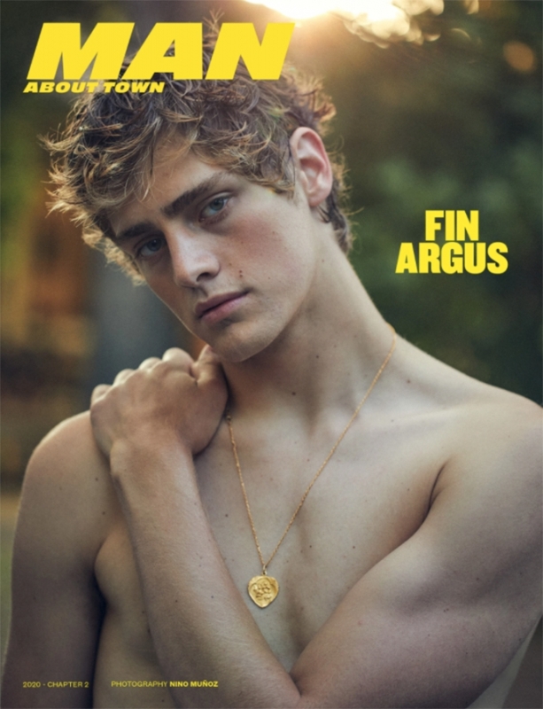 Magazine cover featuring a shirtless male model with a gold necklace against a blurred outdoor background and bright sunlight.
