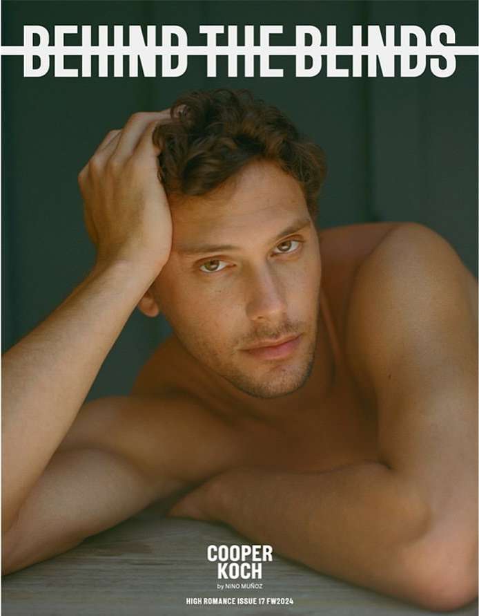 Magazine cover featuring a shirtless adult male with curly hair, looking at the camera while reclining against a neutral backdrop.
