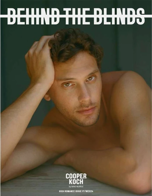 Magazine cover featuring a shirtless adult male with curly hair, looking at the camera while reclining against a neutral backdrop.