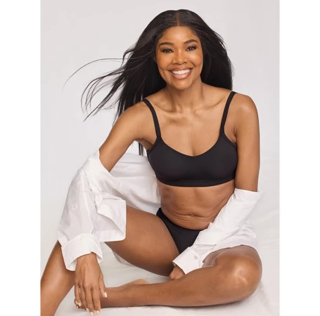 Portrait of Gabrielle Union seated on a white seamless backdrop wearing black undergarments and an open white button-down shirt.