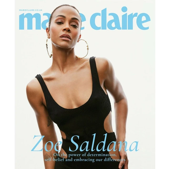 Zoe Saldana cover shot for Marie Claire magazine. Adult woman with gold hoop earrings poses in black, cut-out knit one-piece bathing suit.