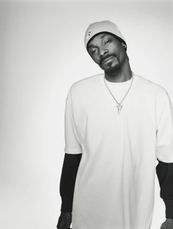 Monochromatic portrait of Snoop Dogg wearing a beanie and a white t-shirt with a silver shark-tooth pendant necklace.