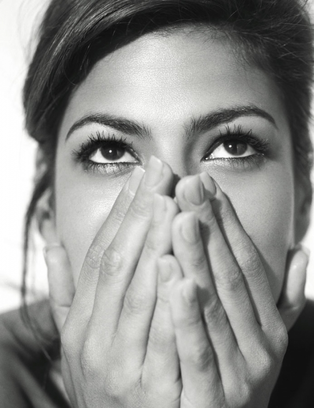 Close-up monochrome portrait of a woman looking upward with hands held loosely covering her lower face, photographed by Sheryl Nields.