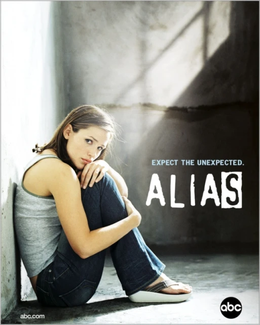Jennifer Garner sits pensively, hugging her legs, in a promotional image for the television show Alias, against a textured gray wall.