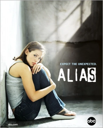 Jennifer Garner sits pensively, hugging her legs, in a promotional image for the television show Alias, against a textured gray wall.