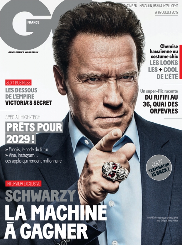 Arnold Schwarzenegger on the cover of GQ France, July 2015. He's pointing with a ring, wearing a dark suit and light shirt, with GQ masthead.