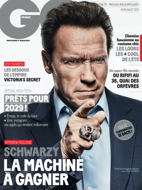 Arnold Schwarzenegger on the cover of GQ France, July 2015. He's pointing with a ring, wearing a dark suit and light shirt, with GQ masthead.