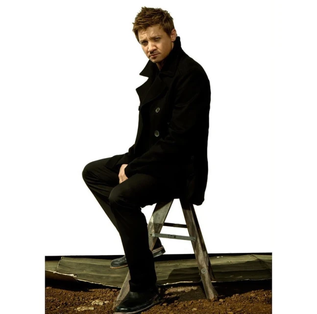Adult male poses on a ladder in a photo studio wearing a black jacket and black pants on a dark surface against a white background.