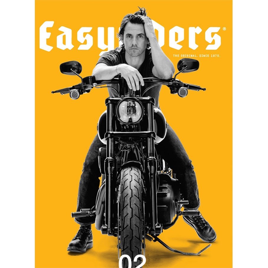 Magazine cover featuring a man with his arm resting on the handlebar of a motorcycle against a bright yellow background.