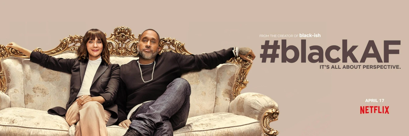 Rashida Jones and Kenya Barris seated together on an ornate carved sofa against a neutral background for BlackAF by Matt Sayles