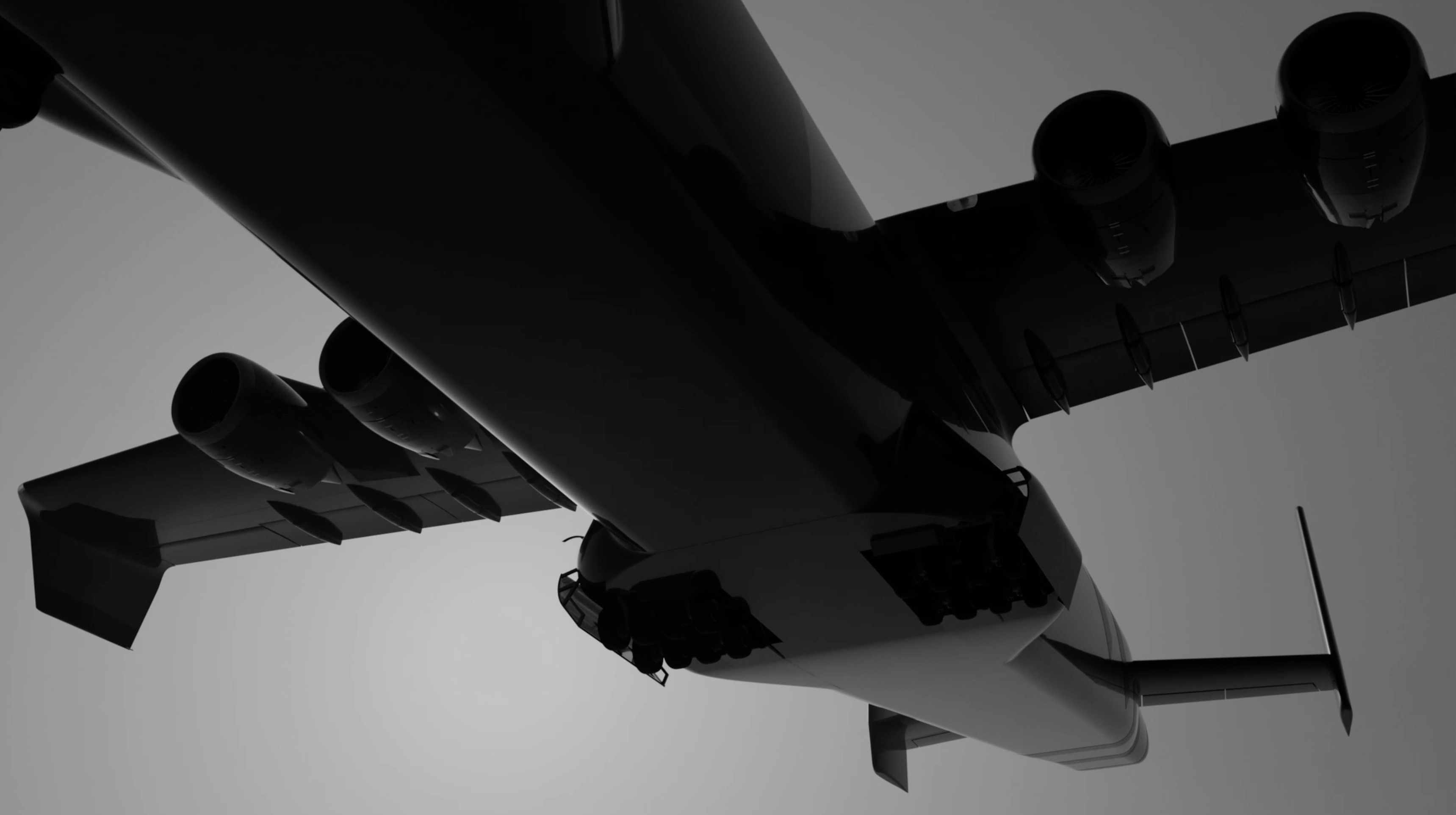 Low-angle shot of a large airplane in monochrome. Six jet engines are mounted beneath the wing, creating a stark, graphic view against the sky.