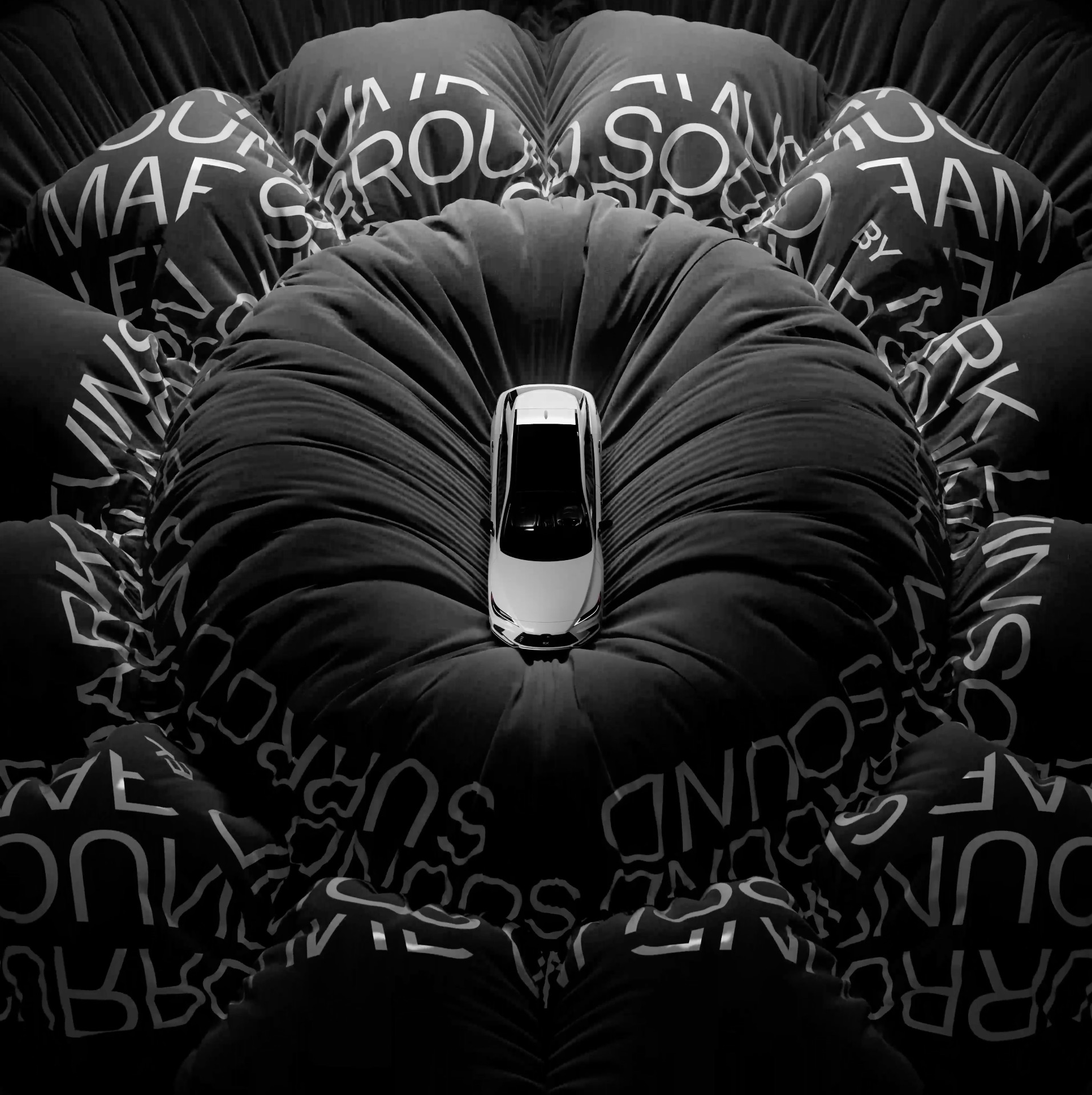 Car sits atop a padded black surface with white text creating a floral effect in a studio-lit automotive product shot.