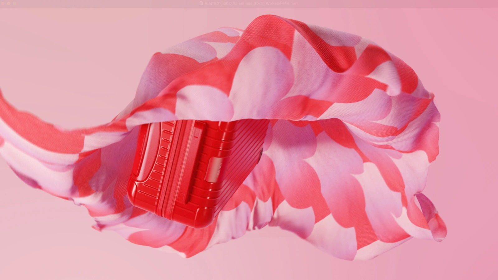 A glossy red ribbed suitcase levitating wrapped inside a floating pink and red floral silk scarf against a pink backdrop.