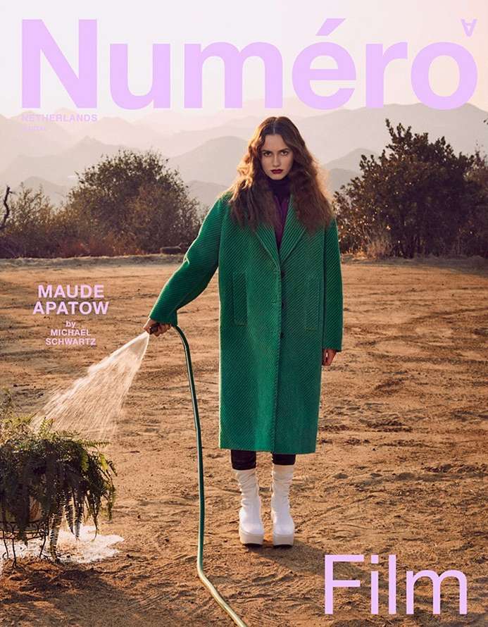 Maude Apatow on the cover of Numero magazine. The model stands in an outdoor landscape wearing a green coat while holding a garden hose.