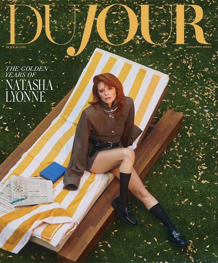 Magazine cover featuring Natasha Lyonne on a striped lounge chair on a lawn, wearing a brown outfit and black loafers.