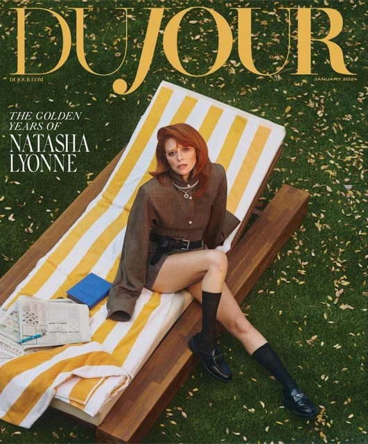 Magazine cover featuring Natasha Lyonne on a striped lounge chair on a lawn, wearing a brown outfit and black loafers.