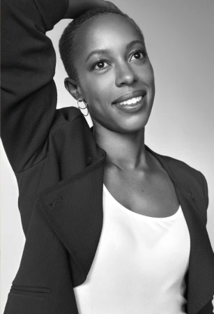 Black-and-white portrait of a smiling woman with short hair wearing a dark jacket and light top, photographed by Michael Schwartz.