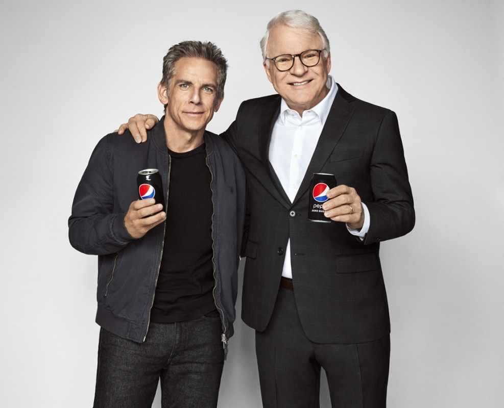 Two adult males pose in a photo studio with Pepsi Zero Sugar cans. Ben Stiller and Steve Martin stand with arms around each other.