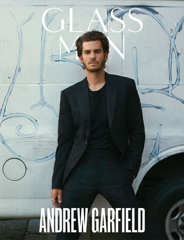 Andrew Garfield poses in a black suit against a backdrop of graffiti on a white van for Glass Man magazine cover, portrait shot.