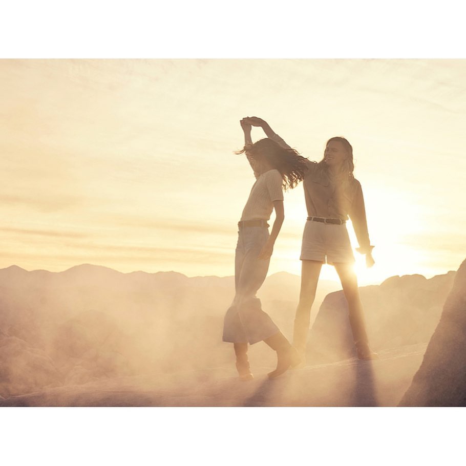 Two women dancing together outdoors in a hazy landscape at sunset captured by Carter Smith