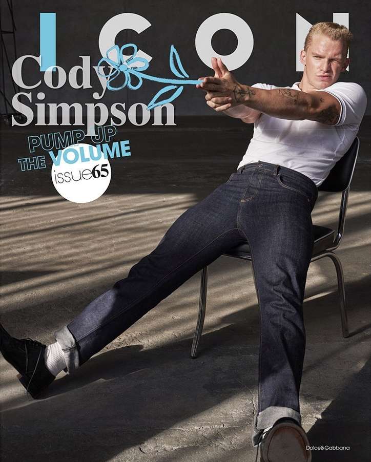 Magazine cover featuring a man seated on a chair, wearing jeans and a white shirt, with hand gestures resembling a gun.