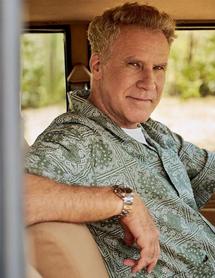 Portrait of Will Ferrell in a car, wearing a patterned green shirt and a watch, smiling at the camera.